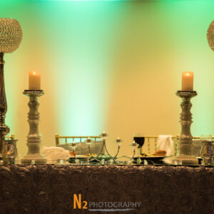 Table with ornate candles, wine glasses, and a rose petal table cloth at Alegria Gardens Reception Hall in Houston.