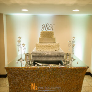 Cake with white rose petals on top of a sparkling table cloth at Alegria Gardens Reception Hall in Houston.