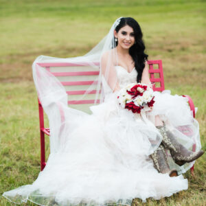 Bridge wearing a white dress and carrying flowers outside of Alegria Gardens Reception Hall in Houston.