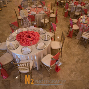 View of tables with red centerpieces at our reception hall - Alegria Gardens