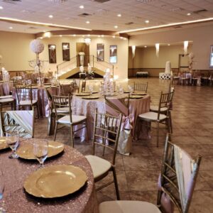 A close-up shot of decorated tables and chairs inside of the dining hall at Alegria Gardens Reception Hall at Stacy in Houston.