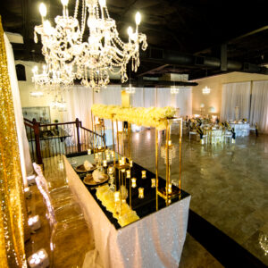 A picture taken from a raised platform at Alegria Gardens at 529 in Houston featuring a gorgeous chandelier, a decorated table, and two chairs.